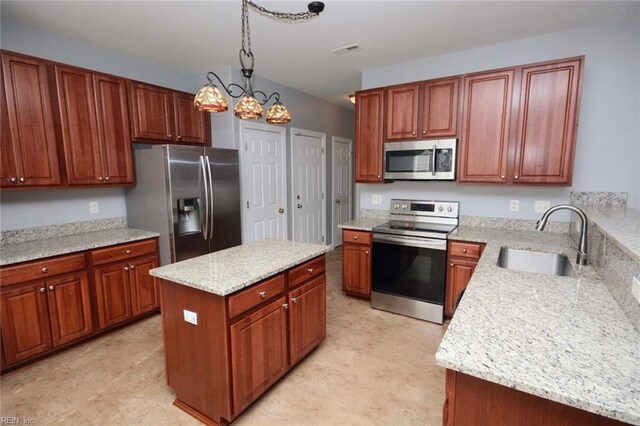 kitchen featuring light stone countertops, appliances with stainless steel finishes, sink, a kitchen island, and decorative light fixtures