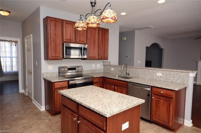 kitchen featuring appliances with stainless steel finishes, sink, a center island, hanging light fixtures, and light stone counters