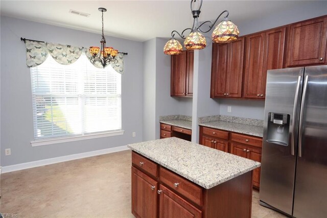 kitchen featuring a center island, decorative light fixtures, light stone counters, a chandelier, and stainless steel refrigerator with ice dispenser