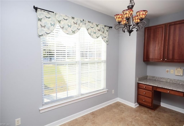 unfurnished office featuring built in desk and a notable chandelier