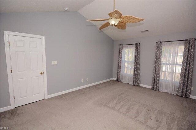 carpeted empty room featuring a wealth of natural light, vaulted ceiling, and ceiling fan