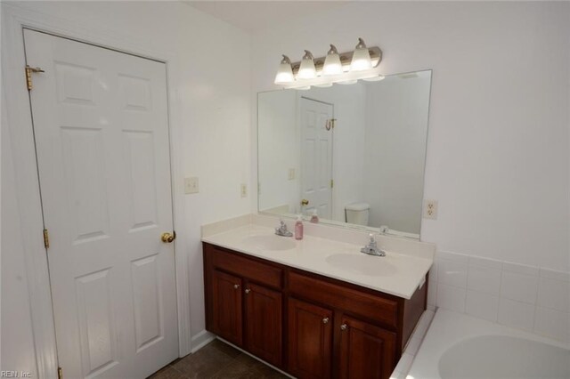 bathroom featuring toilet, a tub, vanity, and tile patterned floors