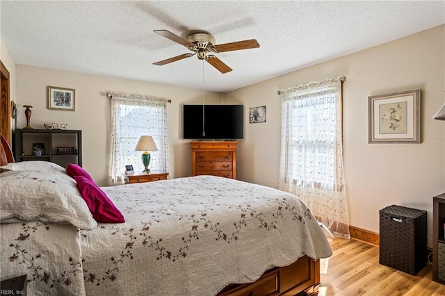 bedroom with light hardwood / wood-style floors, a textured ceiling, and ceiling fan