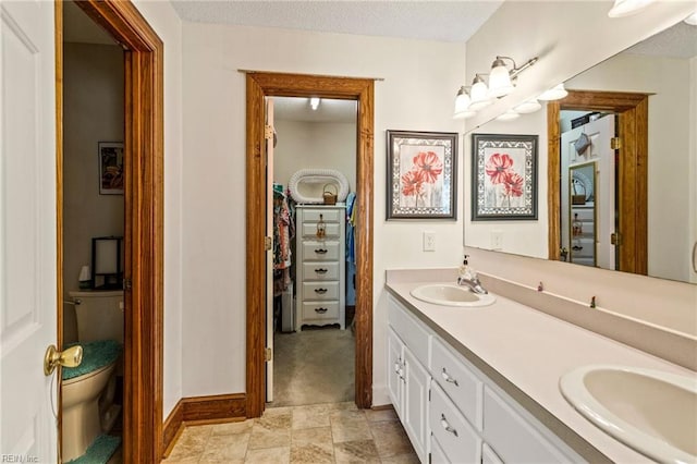 bathroom featuring vanity, a textured ceiling, and toilet