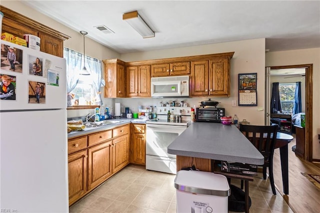 kitchen with light hardwood / wood-style flooring, sink, pendant lighting, and white appliances