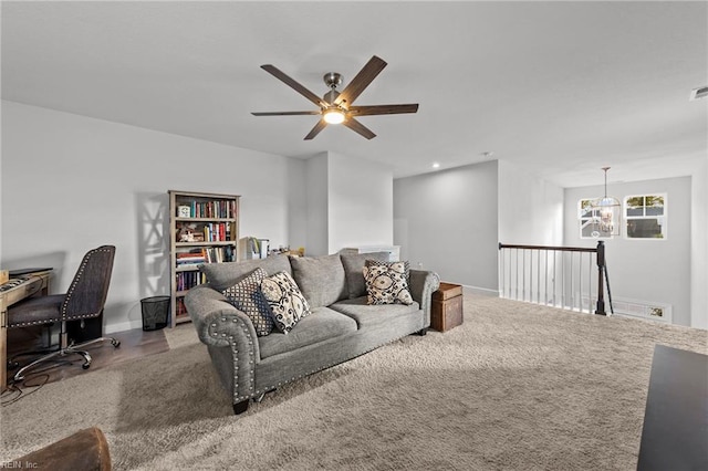 living room featuring light colored carpet and ceiling fan with notable chandelier