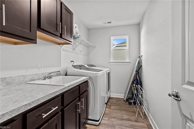 washroom with cabinets, sink, washing machine and clothes dryer, and hardwood / wood-style floors