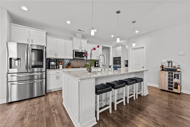 kitchen with appliances with stainless steel finishes, white cabinets, and a center island with sink