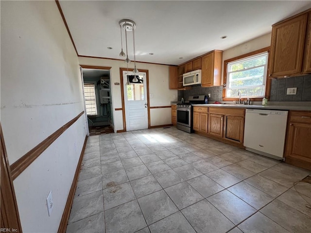 kitchen featuring tasteful backsplash, light tile patterned flooring, pendant lighting, sink, and white appliances