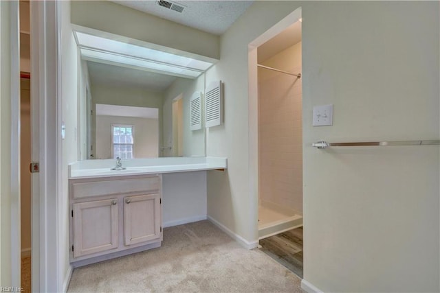 bathroom featuring vanity, a shower, hardwood / wood-style flooring, and a textured ceiling