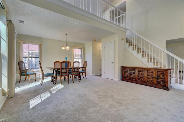 carpeted dining room featuring an inviting chandelier and a textured ceiling