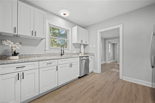 kitchen featuring white cabinets, light stone counters, stainless steel dishwasher, light hardwood / wood-style flooring, and sink