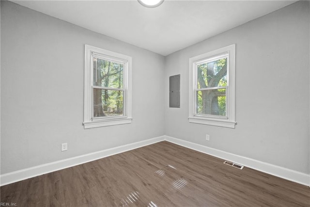 unfurnished room with electric panel, dark hardwood / wood-style flooring, and plenty of natural light