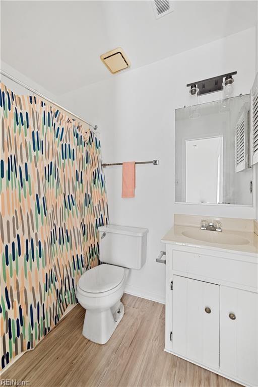 bathroom featuring vanity, curtained shower, wood-type flooring, and toilet