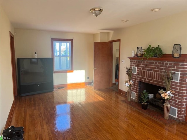 unfurnished living room with a brick fireplace and wood-type flooring