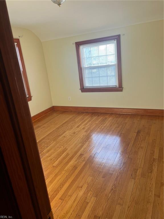 unfurnished room with light hardwood / wood-style floors and lofted ceiling