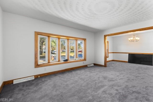 unfurnished living room featuring a chandelier and dark colored carpet