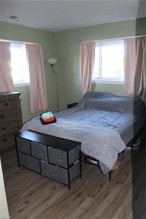 bedroom with multiple windows and dark hardwood / wood-style floors