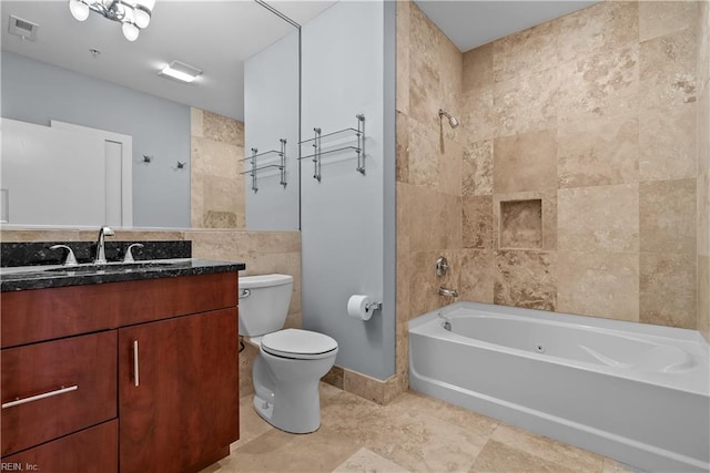 full bathroom with toilet, tiled shower / bath combo, vanity, and tile walls