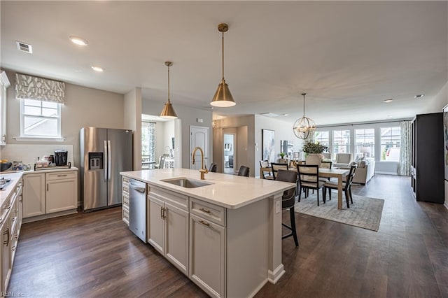 kitchen with a center island with sink, pendant lighting, stainless steel appliances, and plenty of natural light