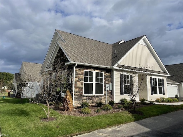 exterior space featuring roof with shingles, a front lawn, stone siding, a garage, and board and batten siding
