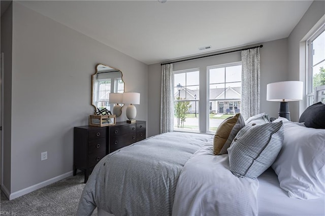carpeted bedroom featuring visible vents, baseboards, and multiple windows