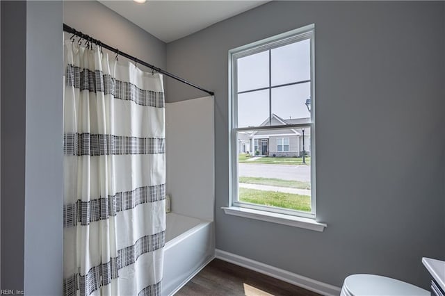 full bathroom featuring baseboards, shower / bath combo with shower curtain, wood finished floors, and toilet
