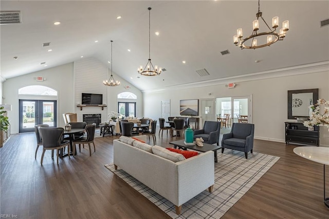 living room featuring an inviting chandelier, a large fireplace, dark hardwood / wood-style floors, and french doors