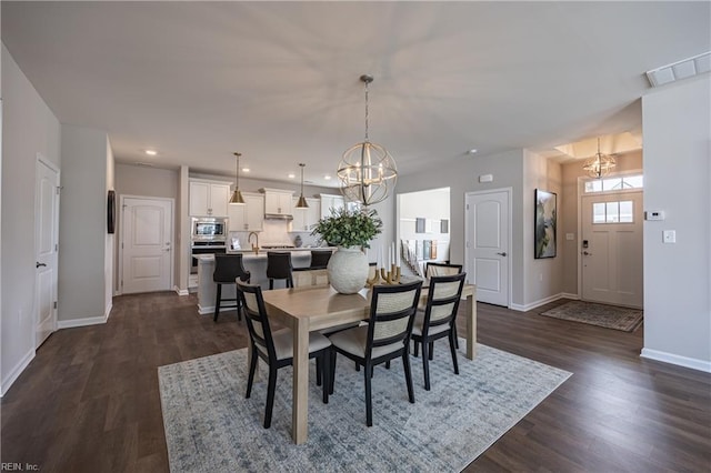 dining space featuring an inviting chandelier, dark wood-style flooring, visible vents, and baseboards