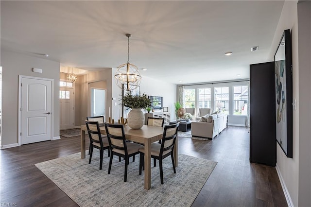 dining space with dark wood-type flooring and a notable chandelier