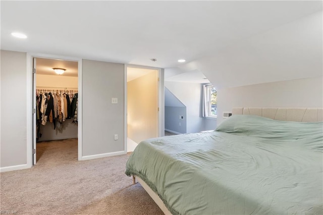 carpeted bedroom with vaulted ceiling, a walk in closet, and a closet