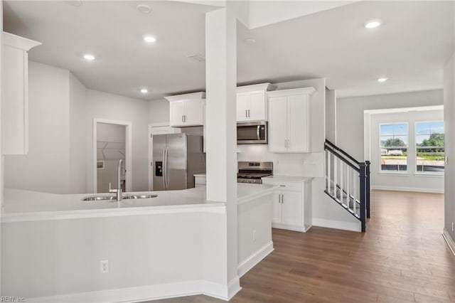 kitchen with white cabinetry, kitchen peninsula, stainless steel appliances, and dark hardwood / wood-style floors