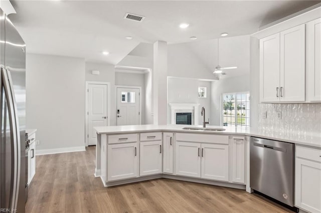 kitchen featuring appliances with stainless steel finishes, sink, kitchen peninsula, light hardwood / wood-style floors, and white cabinets