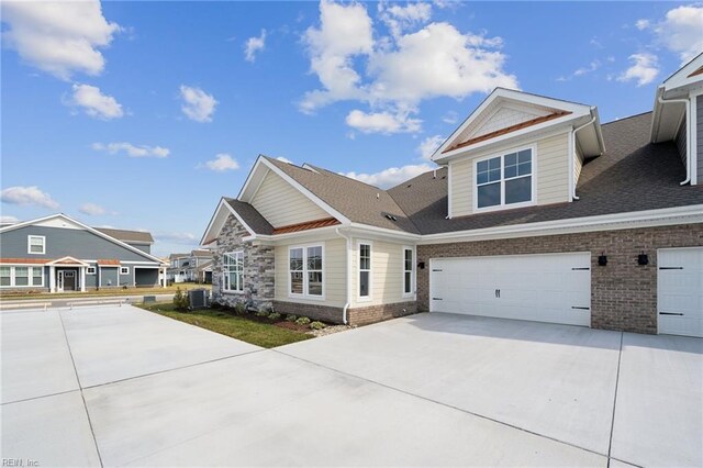craftsman inspired home with an attached garage, a front yard, driveway, and roof with shingles