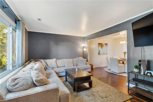 living room featuring crown molding, a notable chandelier, and dark hardwood / wood-style flooring