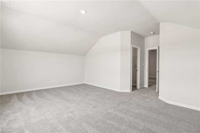 additional living space featuring vaulted ceiling and carpet floors