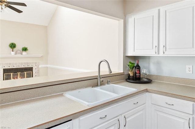 kitchen featuring sink, white cabinetry, a fireplace, and ceiling fan