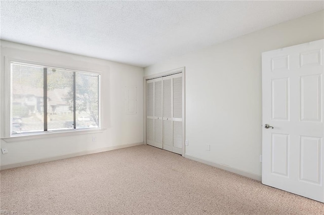 unfurnished bedroom with a closet, a textured ceiling, and light colored carpet