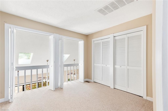 unfurnished bedroom featuring multiple closets, carpet, and a textured ceiling