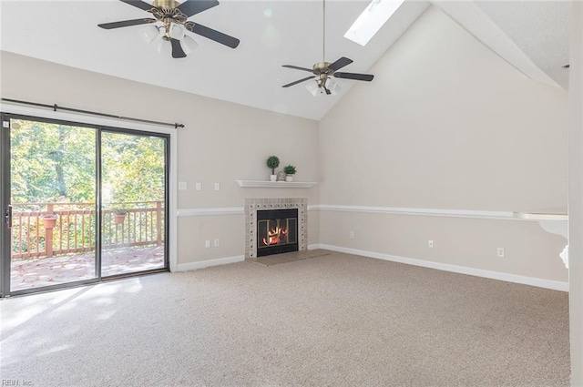 unfurnished living room featuring carpet, a tiled fireplace, high vaulted ceiling, and a skylight