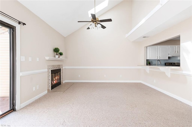 unfurnished living room with light carpet, a tile fireplace, sink, high vaulted ceiling, and ceiling fan