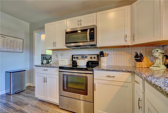 kitchen with appliances with stainless steel finishes, wood-type flooring, white cabinetry, and tasteful backsplash