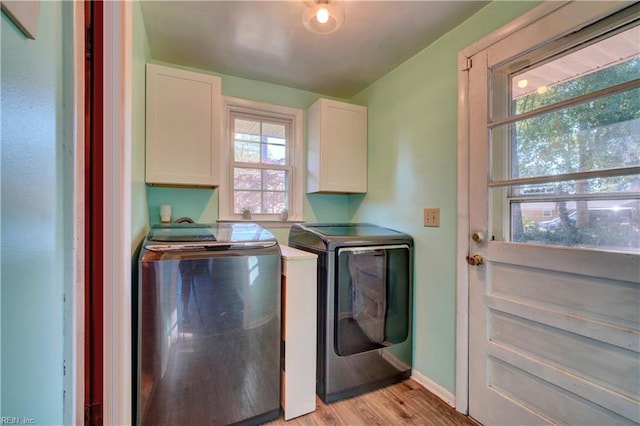 laundry area with cabinets, washer and dryer, and light wood-type flooring