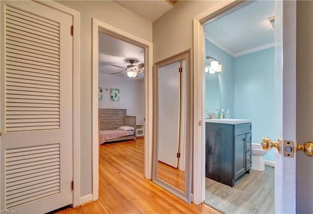 hall with light hardwood / wood-style floors and crown molding