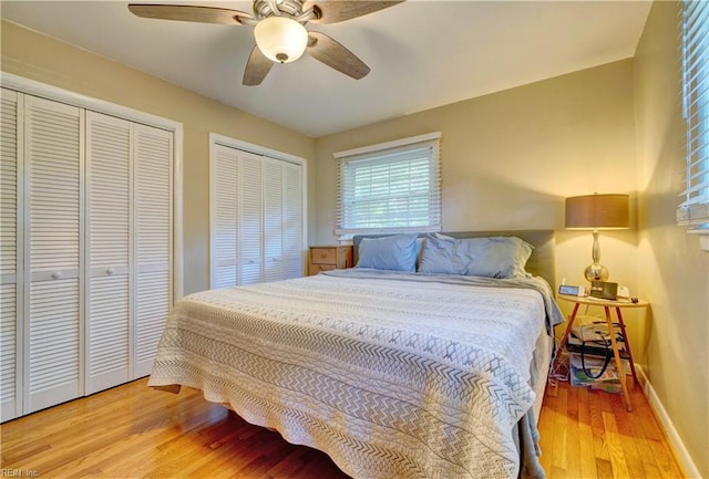 bedroom featuring light hardwood / wood-style floors, multiple closets, and ceiling fan