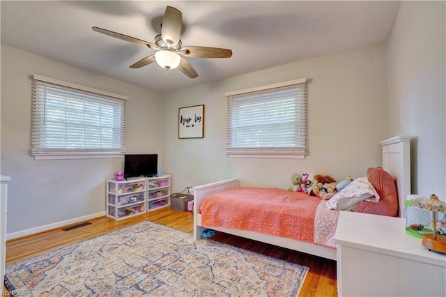 bedroom featuring multiple windows, hardwood / wood-style floors, and ceiling fan