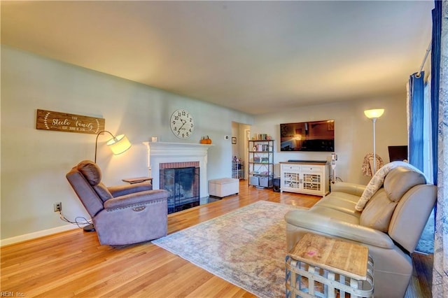 living room with wood-type flooring and a brick fireplace