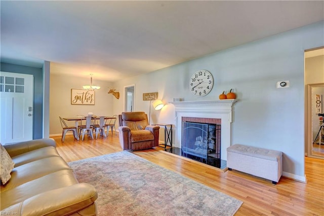 living room with a notable chandelier, hardwood / wood-style flooring, and a fireplace