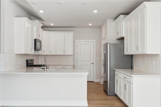 kitchen featuring light hardwood / wood-style flooring, white cabinetry, kitchen peninsula, and stainless steel appliances