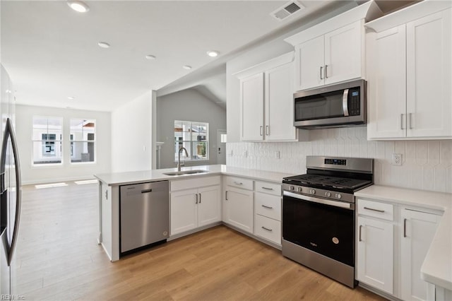 kitchen with sink, stainless steel appliances, vaulted ceiling, white cabinets, and decorative backsplash